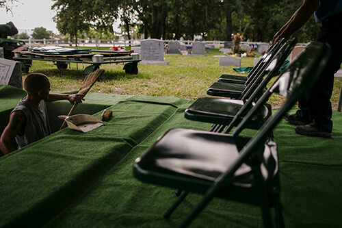 Two groundskeepers prepare a plot for a funeral service at a cemetary in Gulfport, Fla.