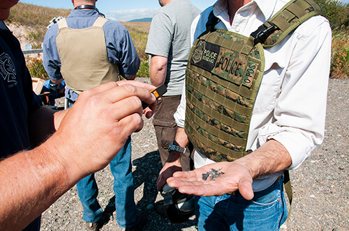 A Forest Service employee takes a photograph of a palmfull of bullet fragments during an ammunition ignition test.