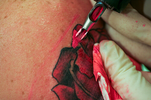 A tattoo artist adds color to a rose for a patron at Painless Steel Tattoo in Missoula, Mont.