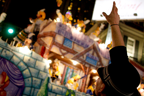 Revellers beg for beads from passing Mardi Gras floats.