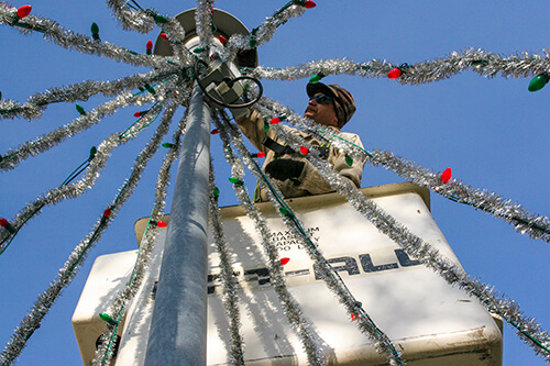 A University of Montana groundskeeper installs holiday decorations on campus.